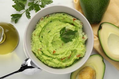 Photo of Delicious guacamole and ingredients on white table, flat lay
