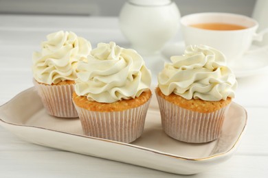 Tasty cupcakes with vanilla cream on white wooden table, closeup