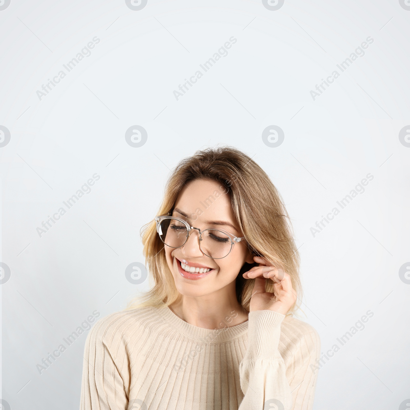 Photo of Portrait of happy young woman with beautiful blonde hair and charming smile on light background