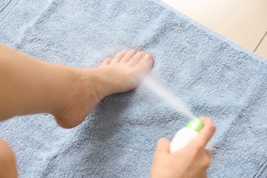 Photo of Young woman using foot deodorant at home, closeup