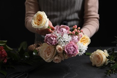 Florist making beautiful bouquet at black table, closeup
