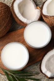 Photo of Glasses of delicious coconut milk, palm leaf and coconuts on table, flat lay