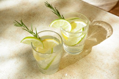 Photo of Glasses of tasty refreshing lemonade on light table. Summer drink
