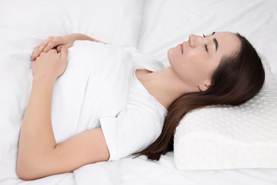 Woman sleeping on orthopedic pillow in bed