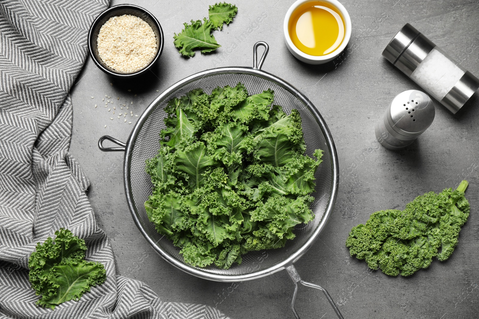 Photo of Raw cabbage leaves on grey table, flat lay. Preparing kale chips