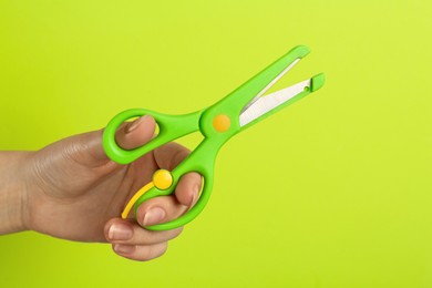 Photo of Woman holding small scissors on light green background, closeup