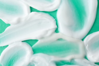 Samples of cream on green background, top view
