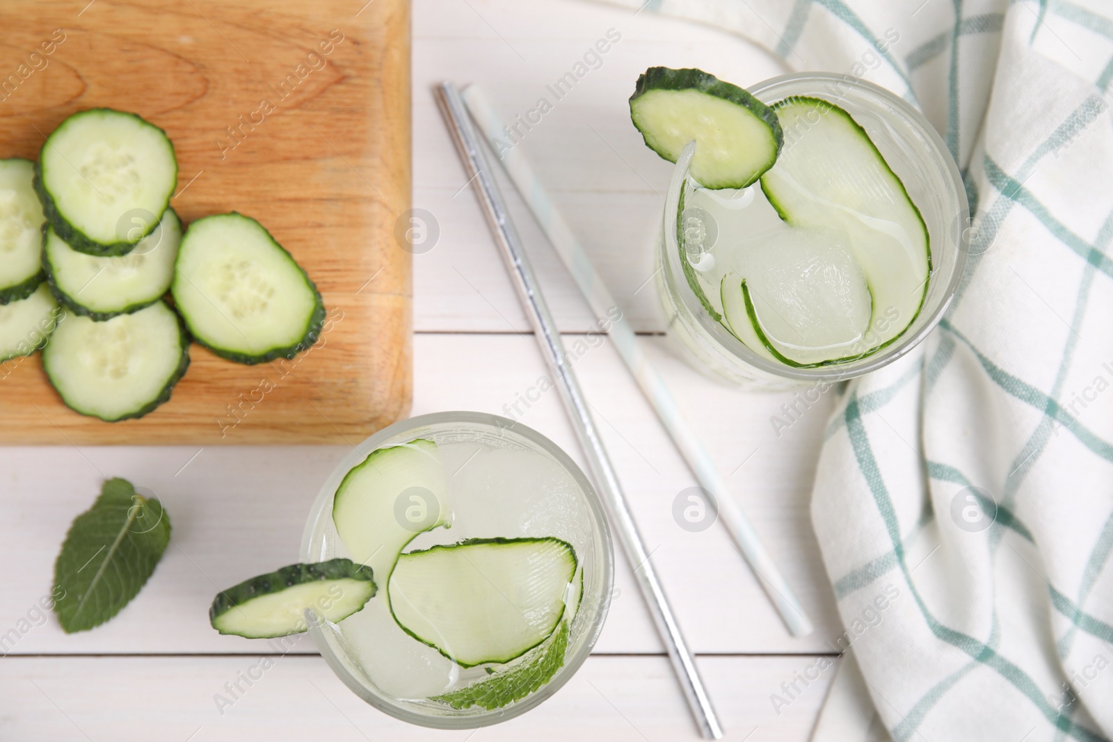 Photo of Tasty fresh cucumber water with mint on white wooden table, flat lay