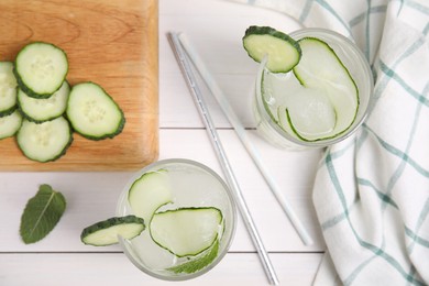 Tasty fresh cucumber water with mint on white wooden table, flat lay