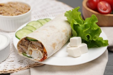 Photo of Delicious tortilla wrap with tuna on grey wooden table