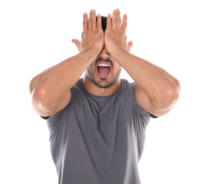 Young man being blinded and covering eyes with hands on white background