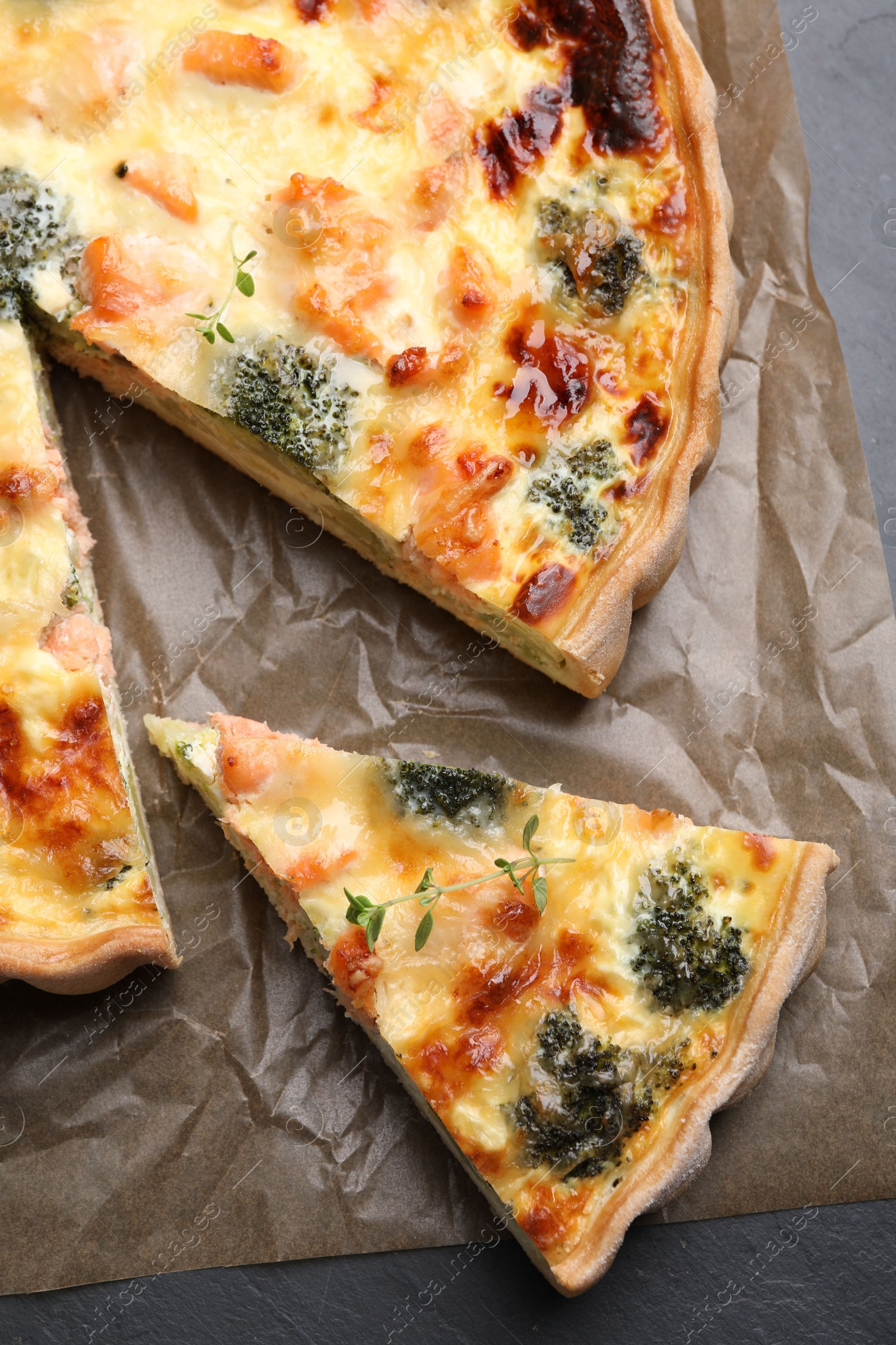 Photo of Delicious homemade quiche with salmon and broccoli on parchment paper, top view