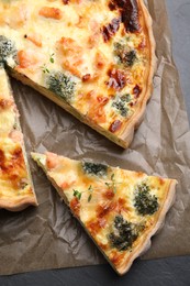 Photo of Delicious homemade quiche with salmon and broccoli on parchment paper, top view