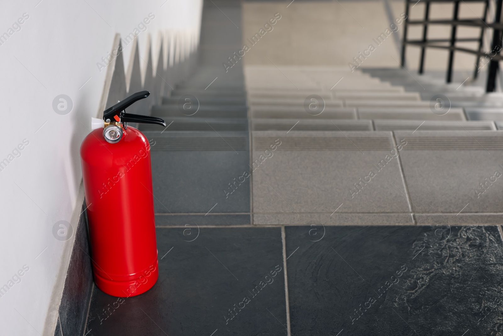 Photo of Red fire extinguisher near white wall, space for text