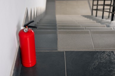 Photo of Red fire extinguisher near white wall, space for text