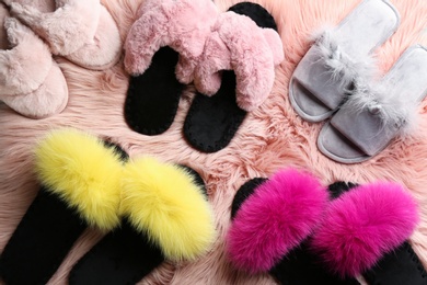 Many different soft slippers on pink faux fur, flat lay