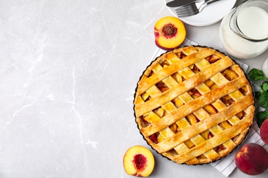 Photo of Delicious fresh peach pie served on light grey table, flat lay. Space for text