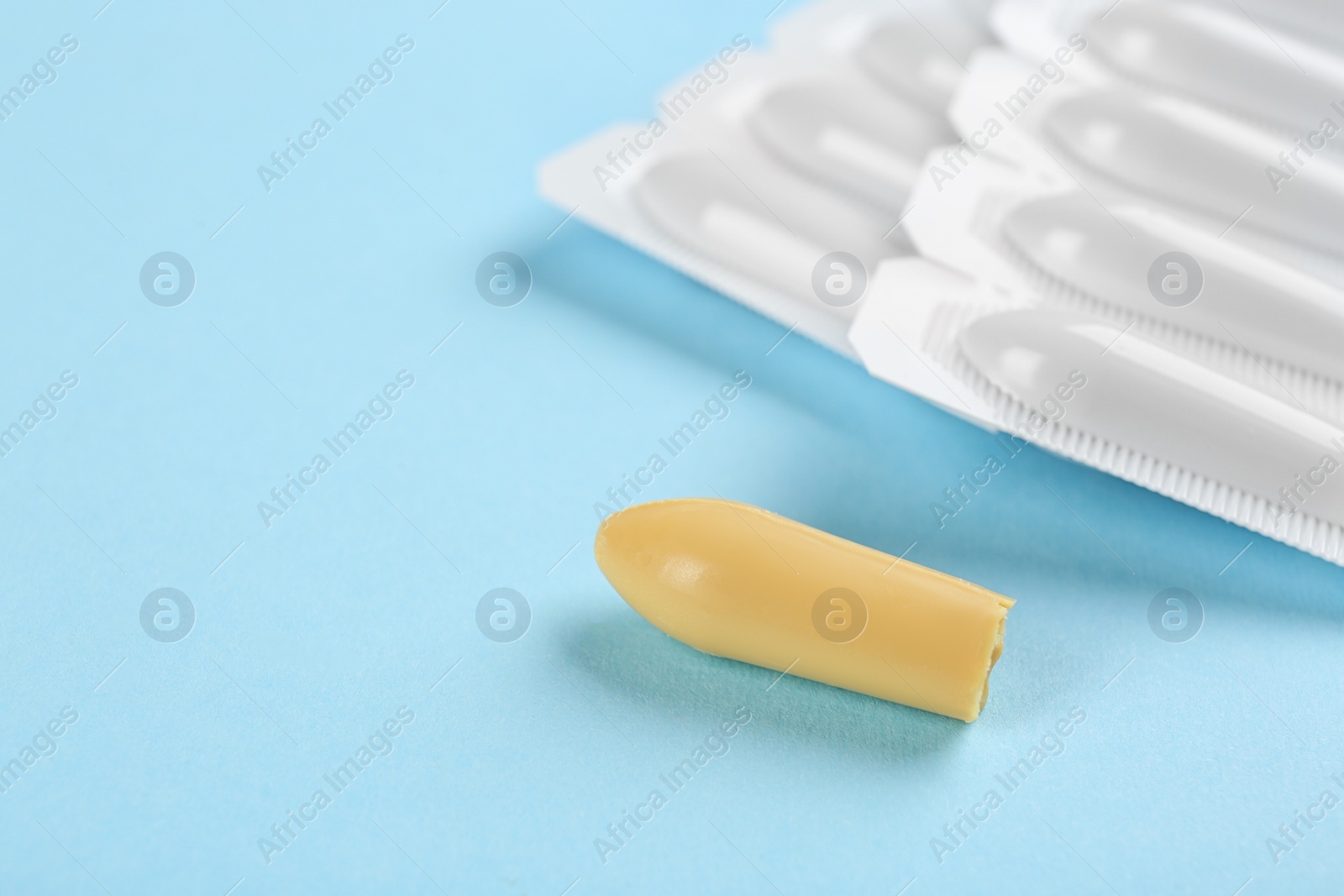 Photo of Suppositories on light blue background. Hemorrhoid treatment