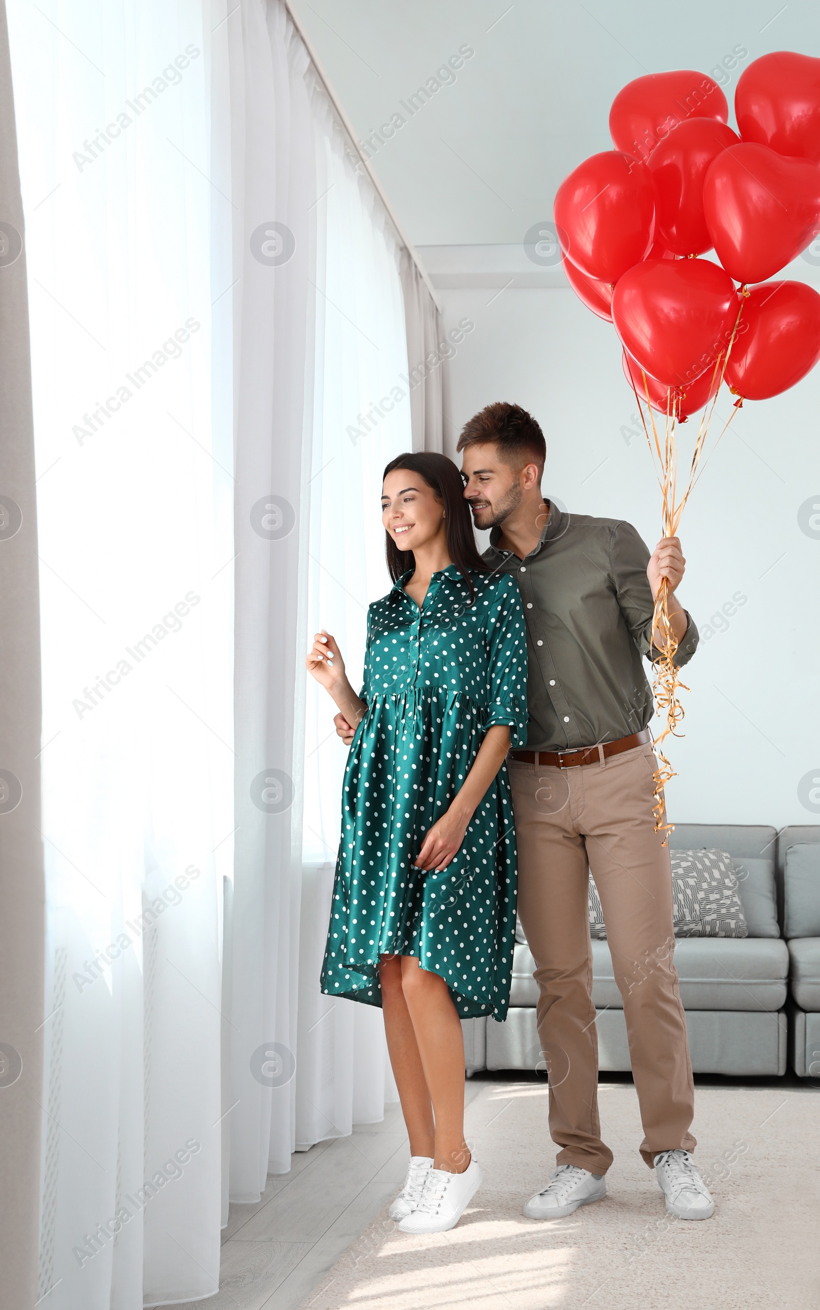 Photo of Young couple with air balloons at home. Celebration of Saint Valentine's Day