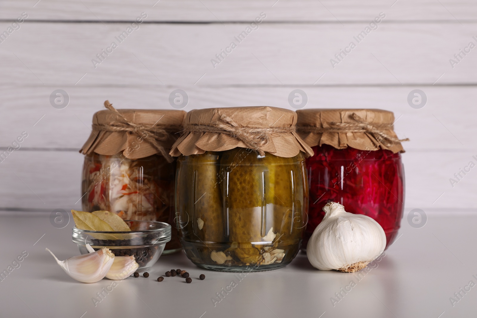 Photo of Jars with different preserved vegetables and fresh spices for canning on light grey table