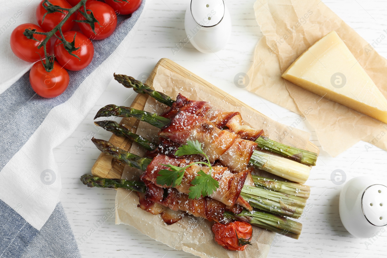 Photo of Oven baked asparagus wrapped with bacon on white wooden table, flat lay