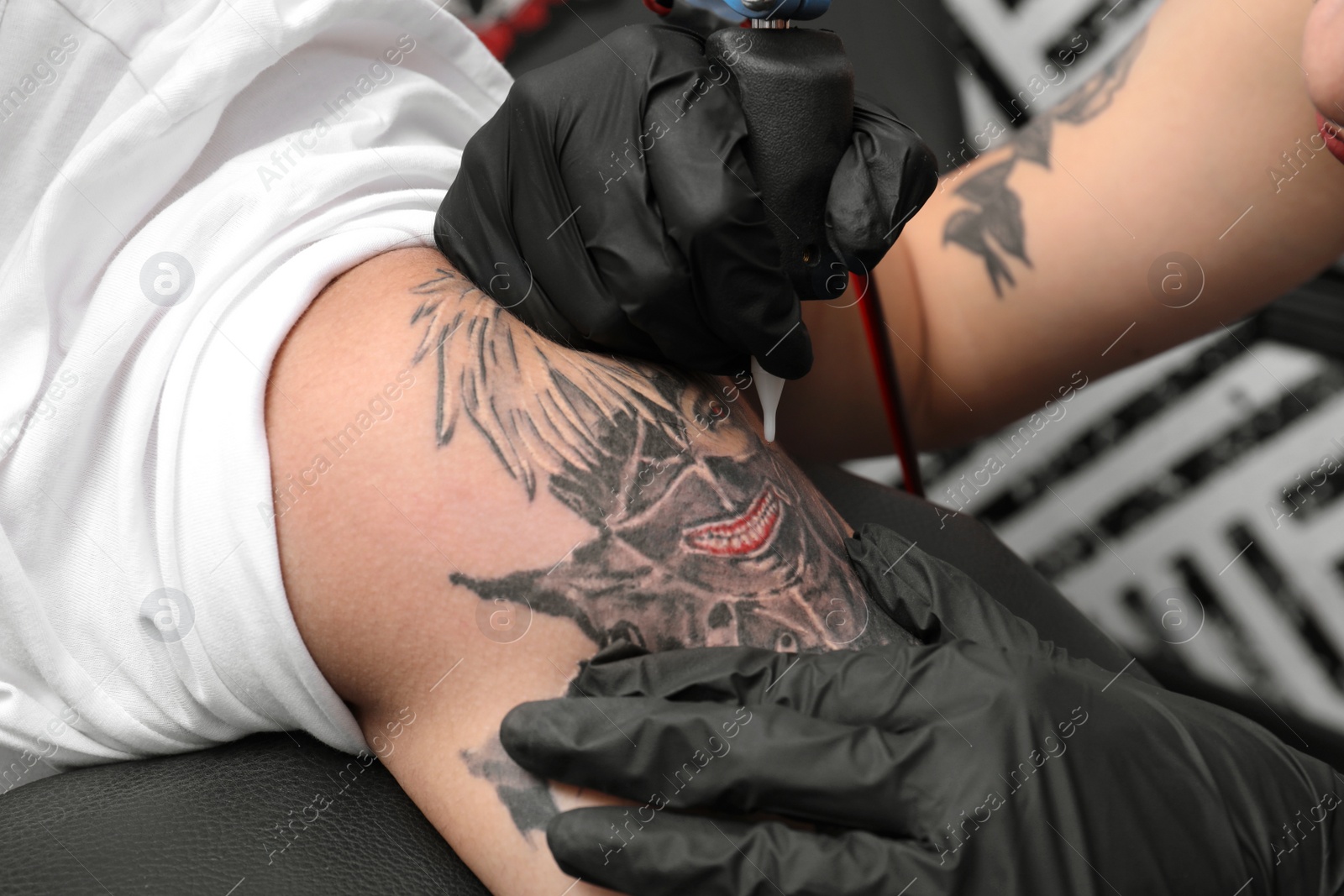 Photo of Professional artist making tattoo in salon, closeup