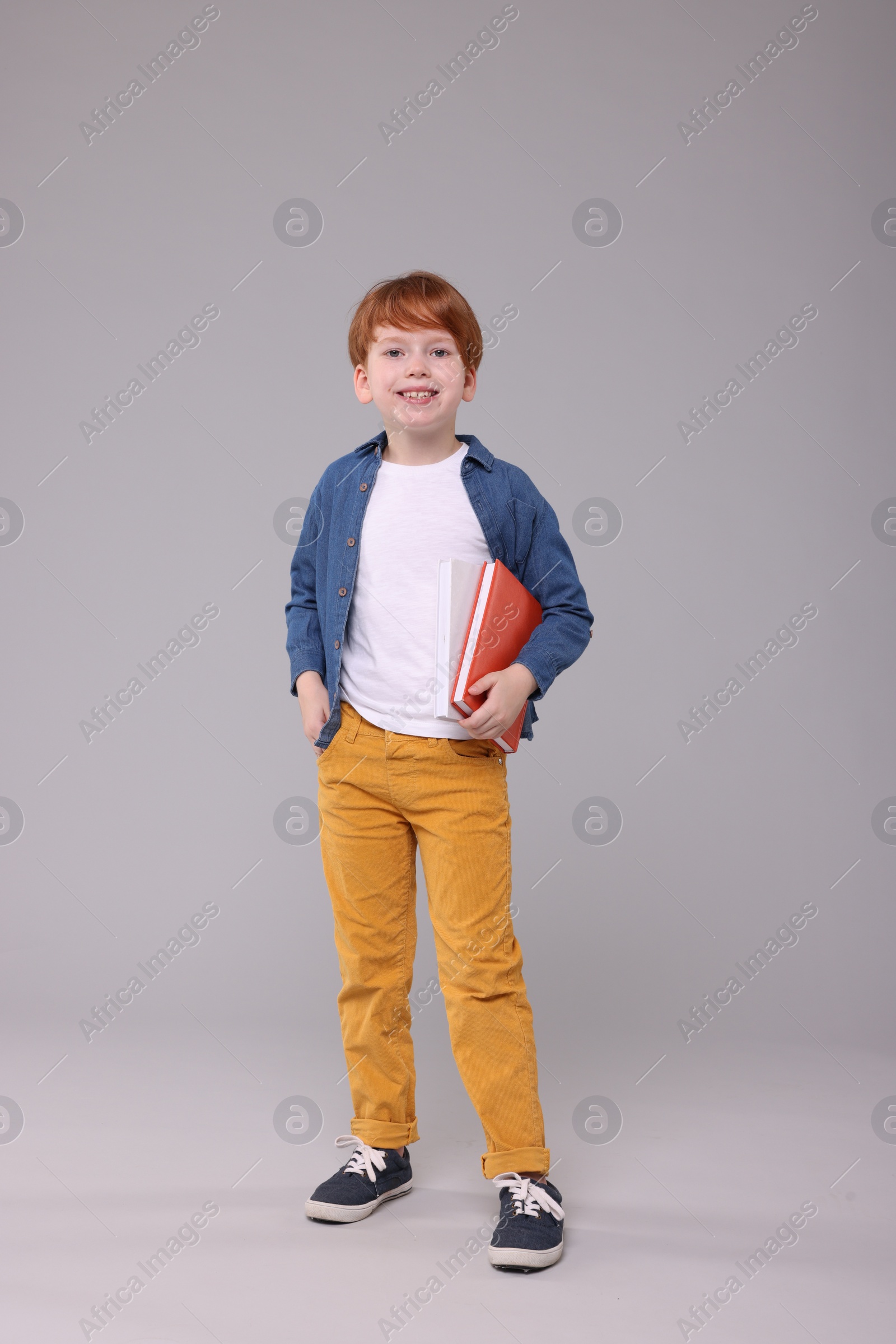 Photo of Happy schoolboy with books on grey background