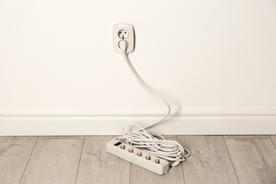 Extension cord with power plug in socket indoors. Electrician's professional equipment