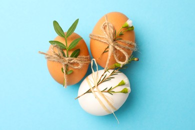 Chicken eggs and natural decor on light blue background, flat lay. Happy Easter