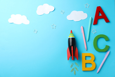 Photo of Bright toy rocket and school supplies on light blue background, flat lay. Space for text