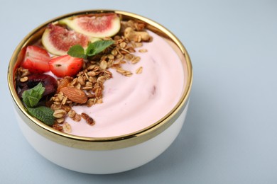 Photo of Bowl with yogurt, fruits and granola on light grey background, closeup. Space for text