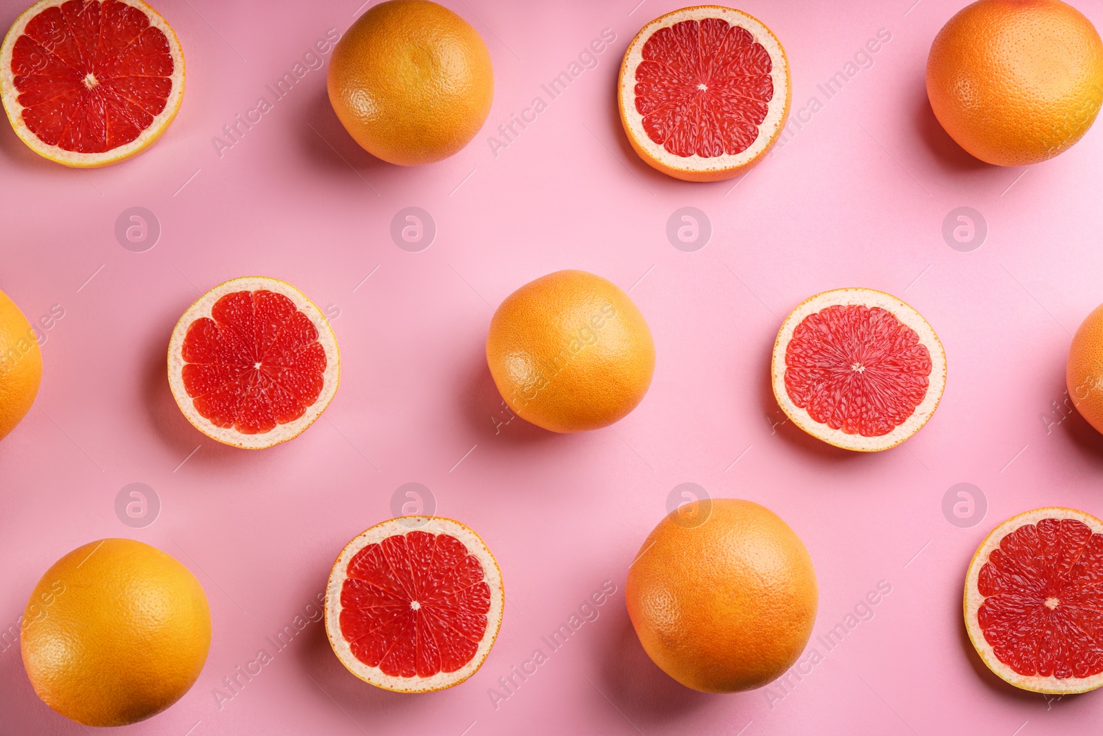 Photo of Cut and whole ripe grapefruits on pink background, flat lay