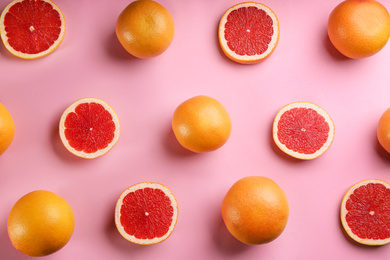 Photo of Cut and whole ripe grapefruits on pink background, flat lay