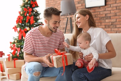 Happy couple with baby celebrating Christmas together at home