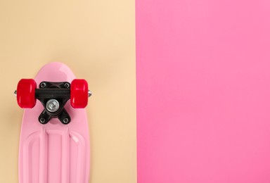 Pink skateboard on color background, top view. Space for text