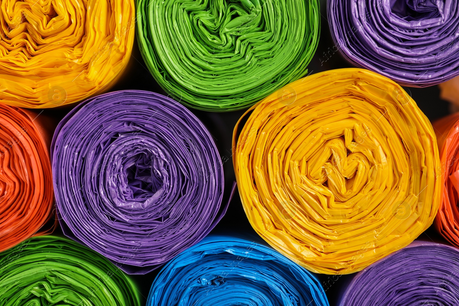 Photo of Rolls of different garbage bags as background, top view