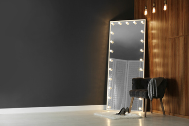 Photo of Modern mirror with lamps in room interior. Space for text