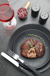 Photo of Tasty grilled beef meat served on black table, flat lay