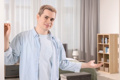Photo of Happy man inviting to come in room