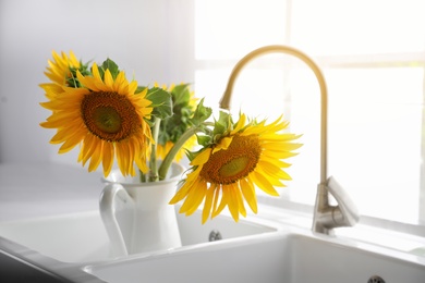 Bouquet of beautiful sunflowers in sink at home