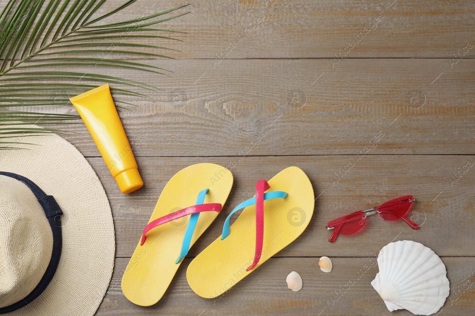 Photo of Stylish flip flops and beach objects on wooden background, flat lay. Space for text