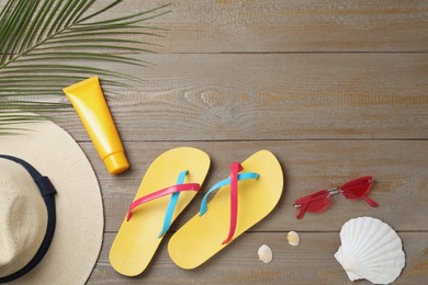 Photo of Stylish flip flops and beach objects on wooden background, flat lay. Space for text