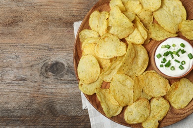 Photo of Chips with sour cream on wooden background, top view. Space for text