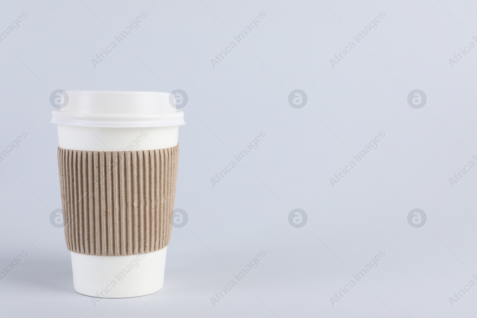 Photo of Paper cup with plastic lid on light background, space for text. Coffee to go