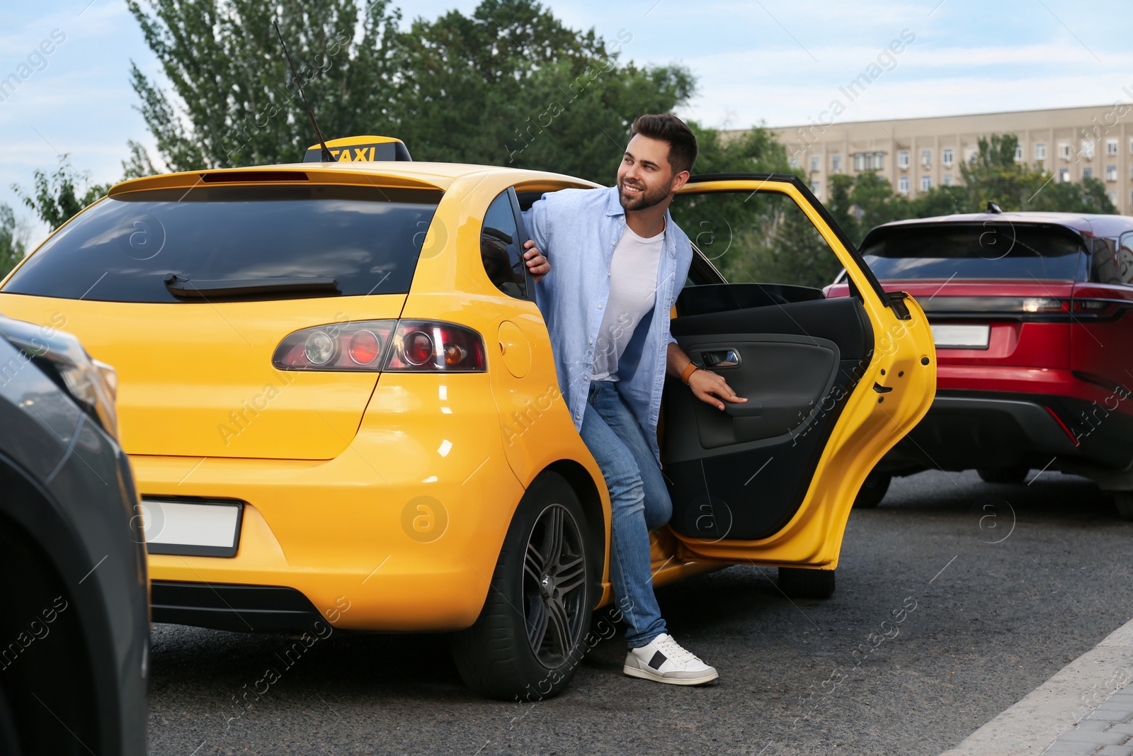 Photo of Handsome young man getting out of taxi on city street