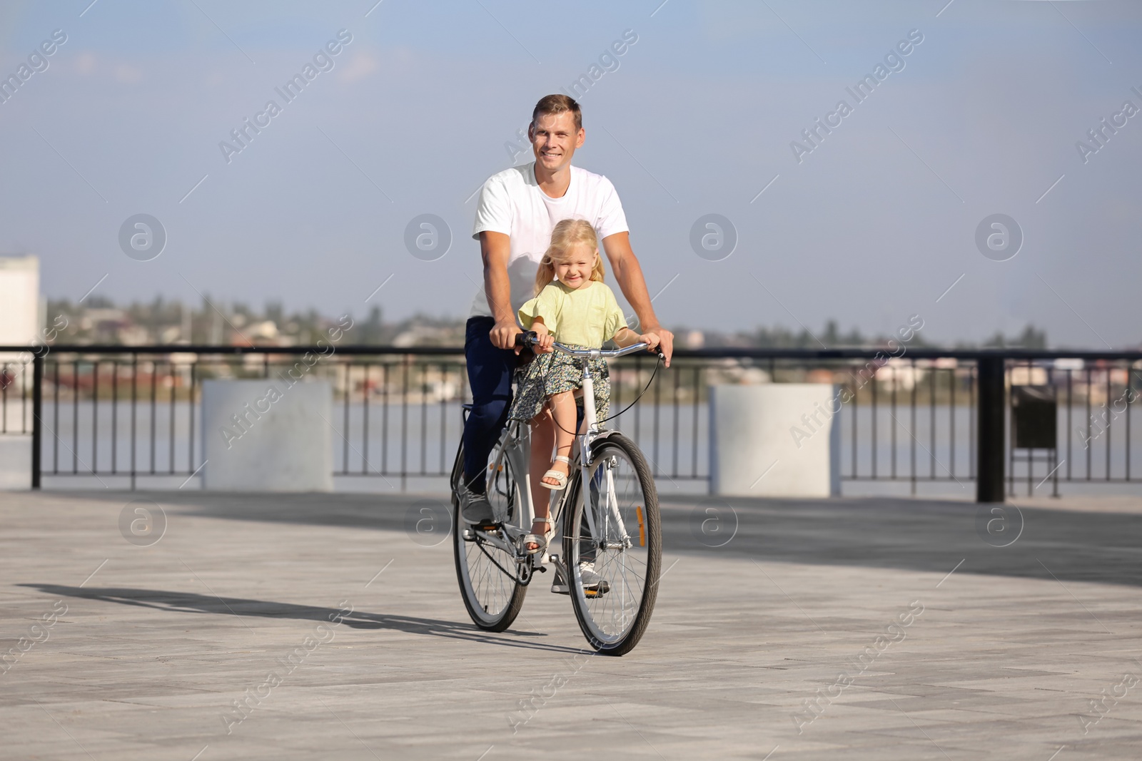 Photo of Father and daughter riding bicycle outdoors on sunny day