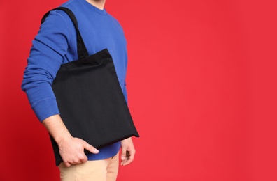 Young man with eco bag on red background, closeup. Space for text