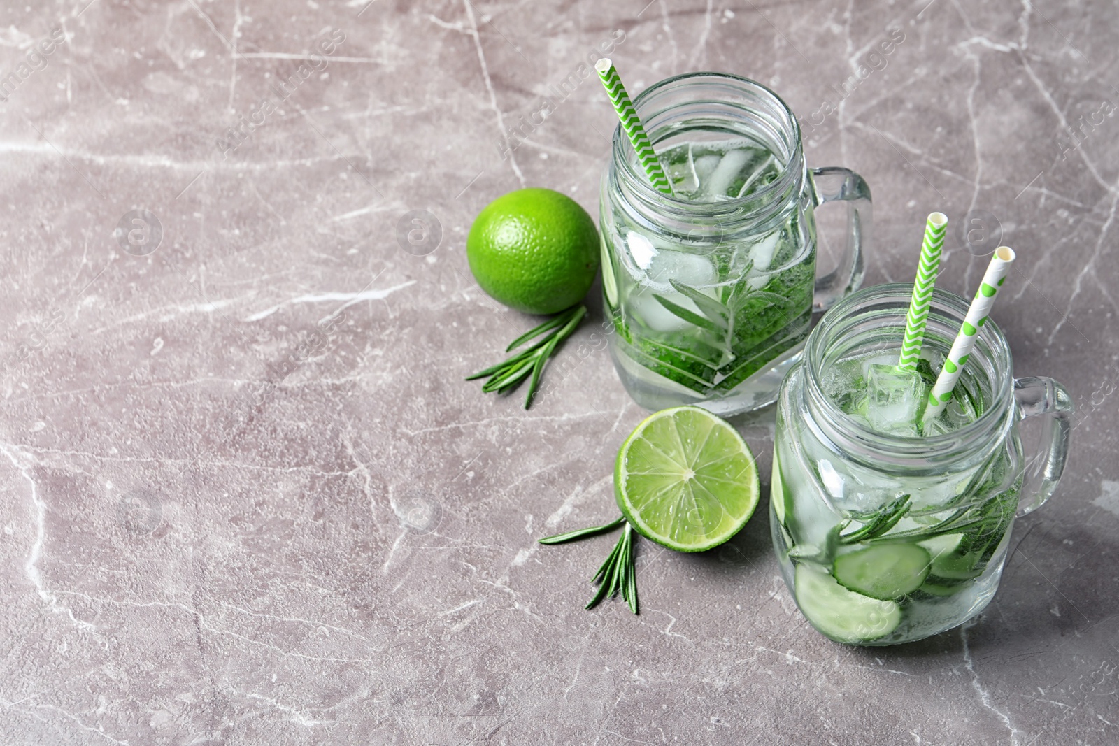 Photo of Natural lemonade with cucumber, lime and rosemary in mason jars on table