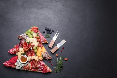 Photo of Fir tree shaped board with different appetizers and sauce on black table, flat lay. Space for text