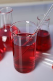 Photo of Laboratory analysis. Different glassware with red liquid on white table indoors, closeup